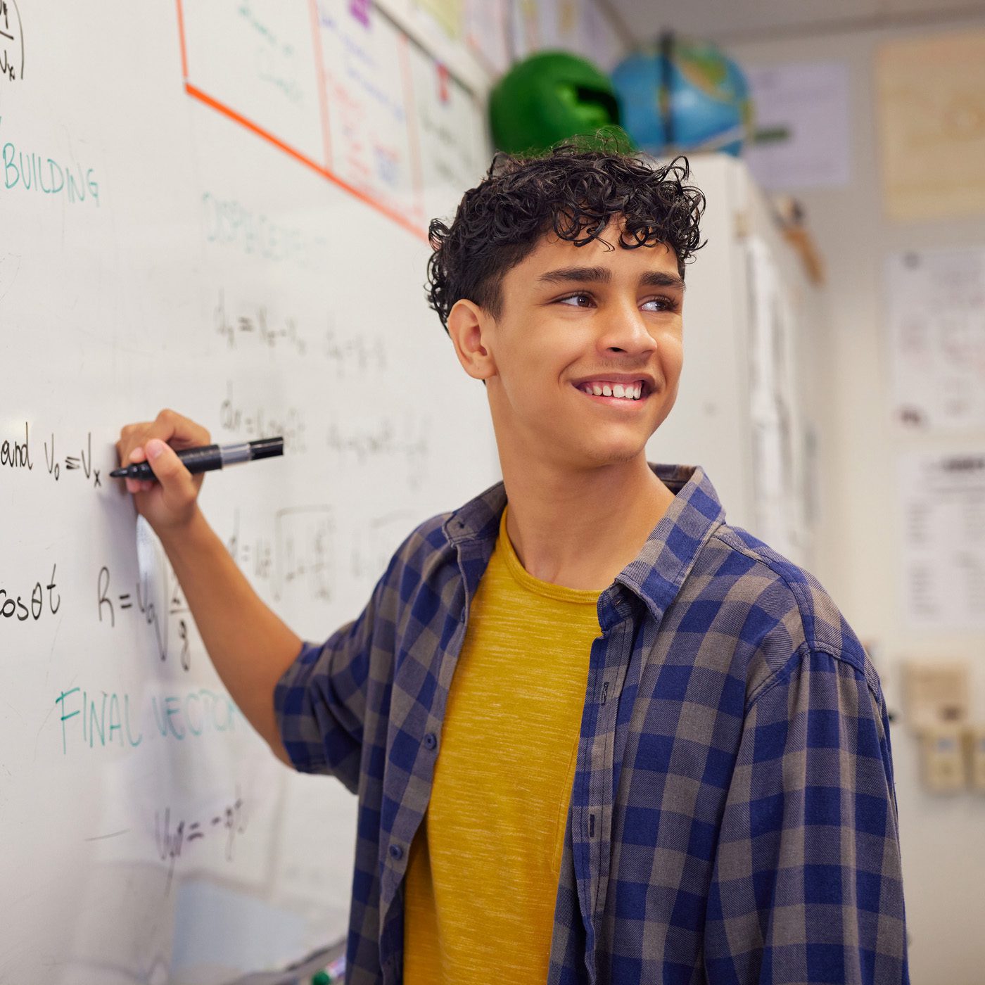 A boy standing at a whiteboard solving a math problem