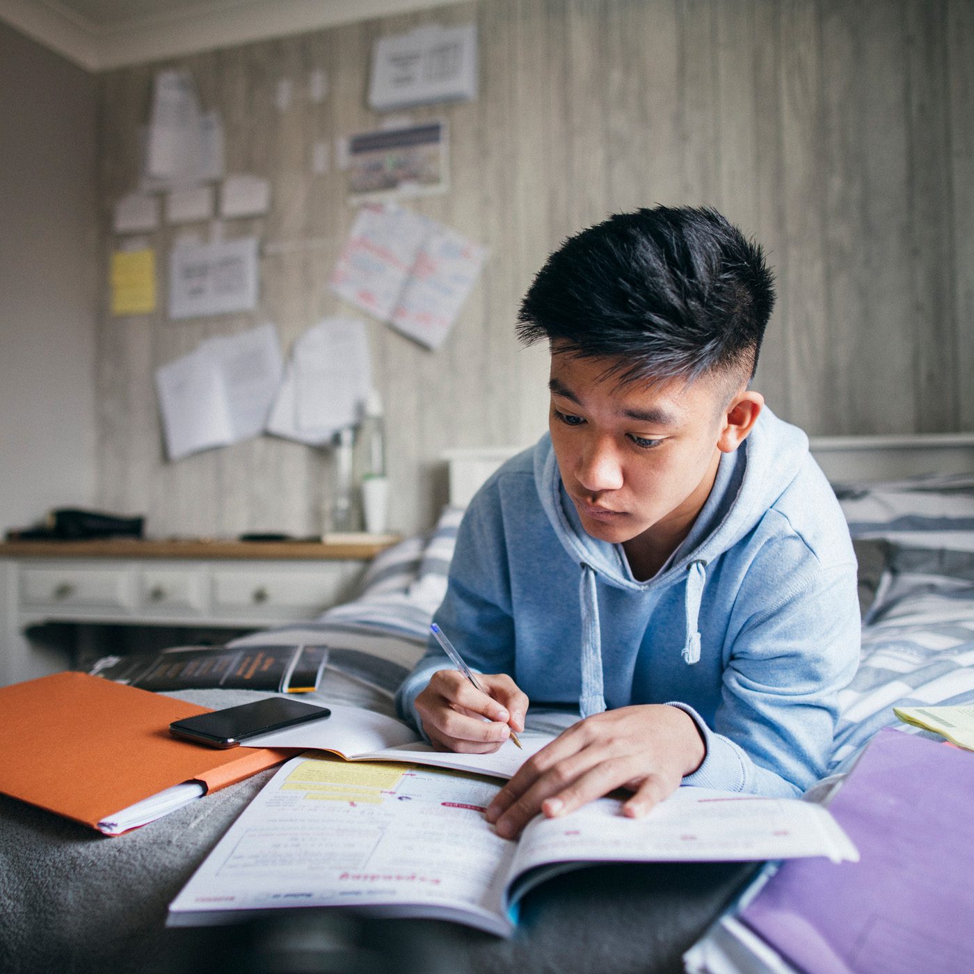 A student laying on his bed doing math homework